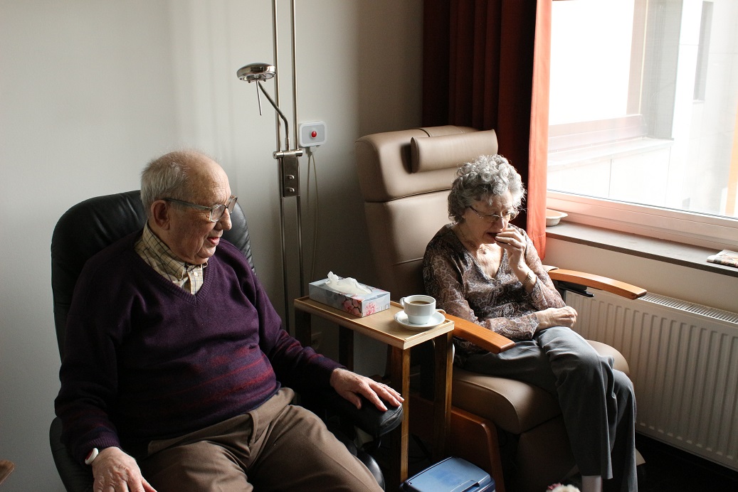 An older couple sitting side-by-side in their lounge room