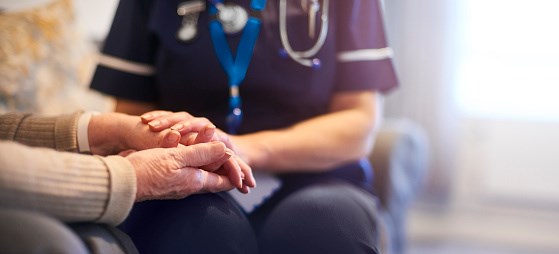 Nurse holds the hands on an elderly person