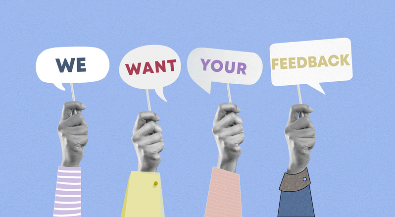 Group of paper hands showing we want your feedback words on speech bubble cards on blue background