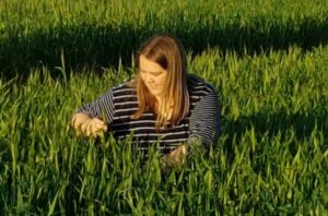 Associate Professor Rhiannon Schilling squatting down in a green field
