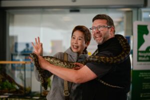 Man and woman holding up a snake