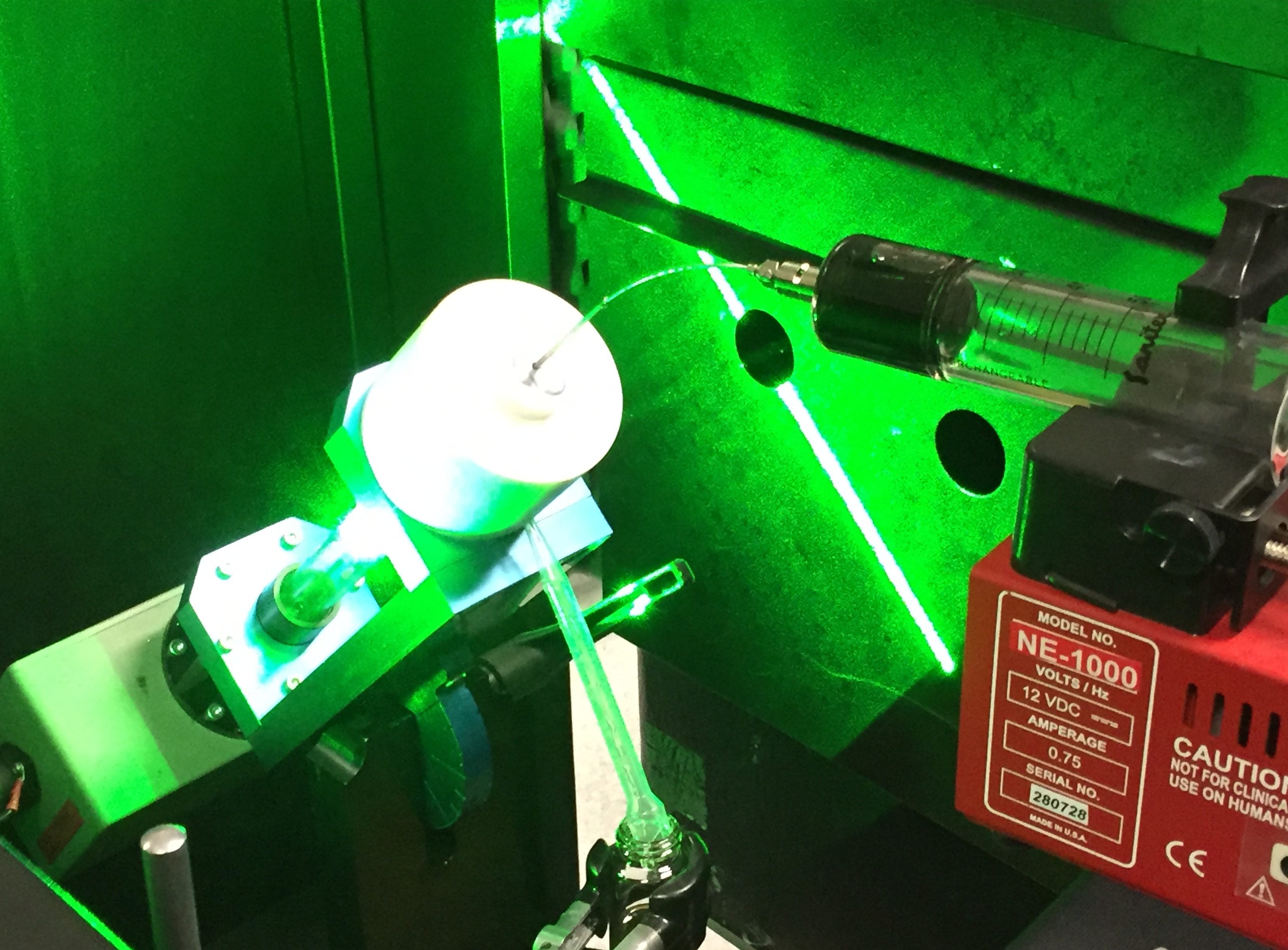 Green laser light reflecting off a Vortex Fluidic Device.
